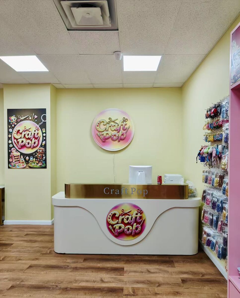 Craft Pop front desk with the pink round logo, framed Craft Pop poster and pink shelves of supplies