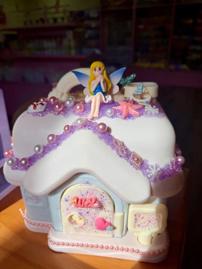 Cream glue fairy house with lavender piping, pearls and a fairy figure