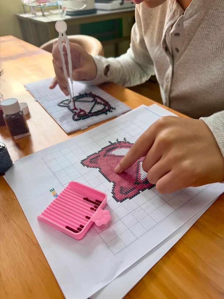 Child placing perler beads on a pegboard following a pixel heart pattern at Craft Pop Astoria