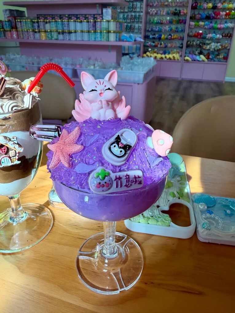 Purple cream glue dessert cup topped with a white kitty charm and colorful decorations